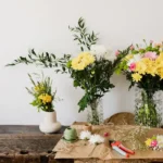 Rangkaian bunga potong segar dalam vas kaca di atas meja